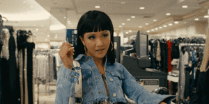A character in the movie Hustlers waving a credit card in her hand.