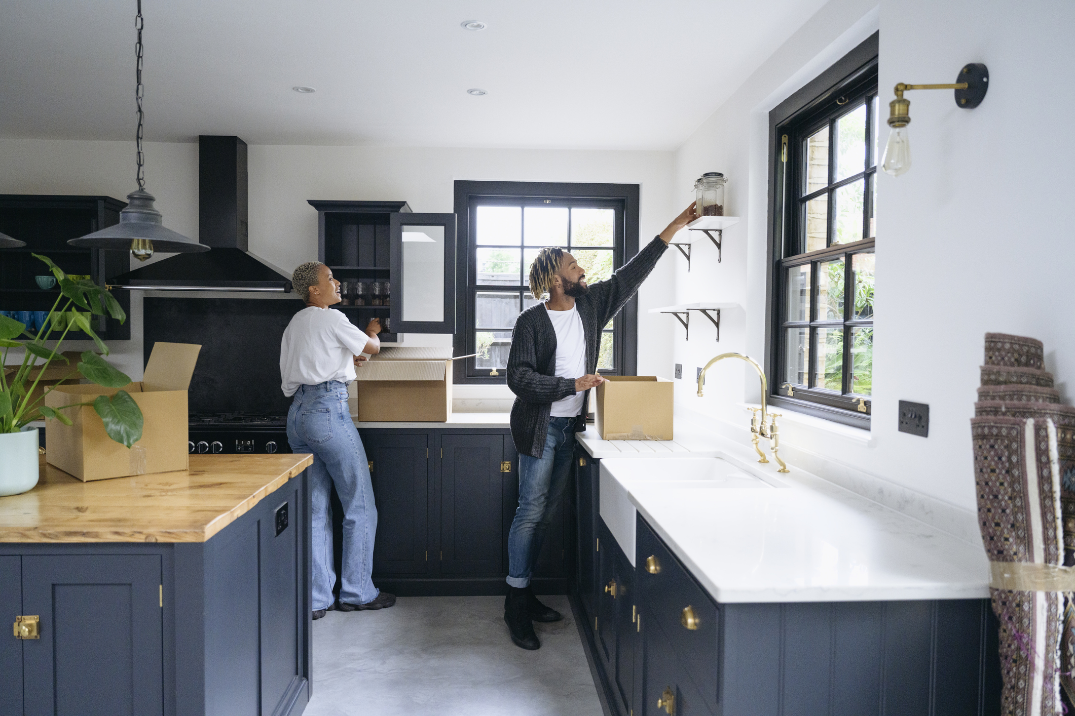 Young couple unpacking boxes in Shaker-style kitchen.