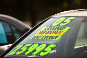 Stickers on the windshield of a car for sale at a used car dealership