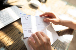 Learn how to read your paycheck - Close-up Of A Businessperson's Hand Opening Envelope With Paycheck Over Wooden Desk