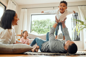 Young parents considering whole life insurance play with their two kids on the floor in their living room
