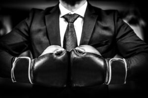 Businessman in a suit wearing boxing gloves prepares to outperform the market