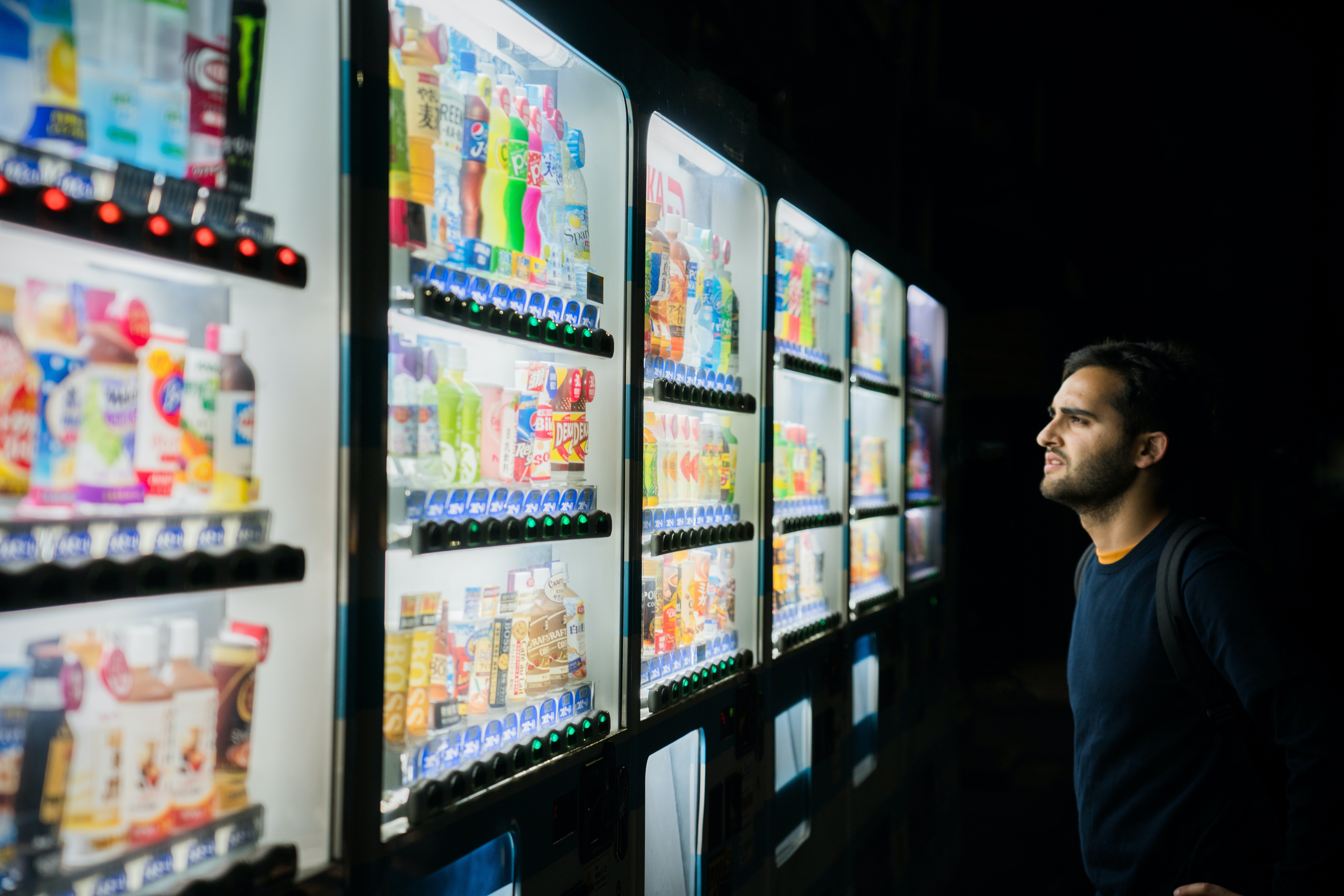A person feeling overwhelmed by their options in front of many vending machines