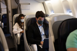 Business people wearing face masks sit in the business class cabin