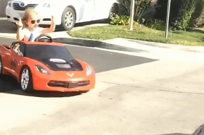 Blonde child in a mini orange corvette drifts out of a driveway