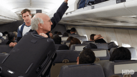Man swinging his bag into overhead compartment in economy class plane cabin
