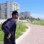University student in cap and gown dances down a brick pathway