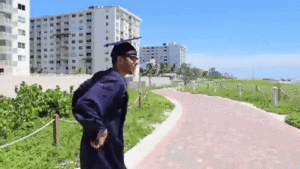 University student in cap and gown dances down a brick pathway